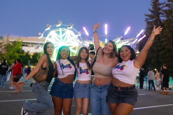 Group posing in front of lit-up carnival