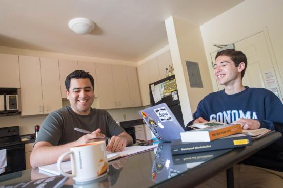 Two students laugh as they study together in a dorm