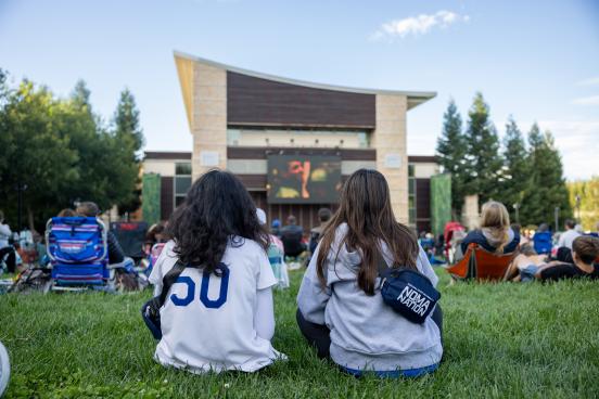 Two students watch a movie on the lawn of Weill Hall