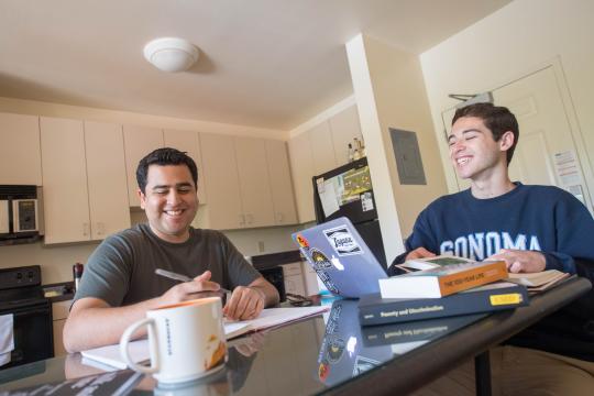 Two students laugh as they study together in a dorm