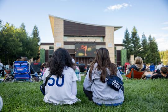 Two students watch a movie on the lawn of Weill Hall