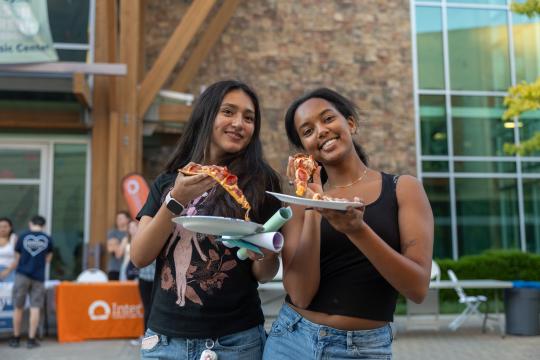 Two students pose with their plates of pizza
