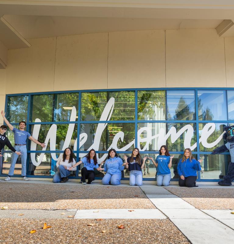 Group of students standing in front of a welcome sign