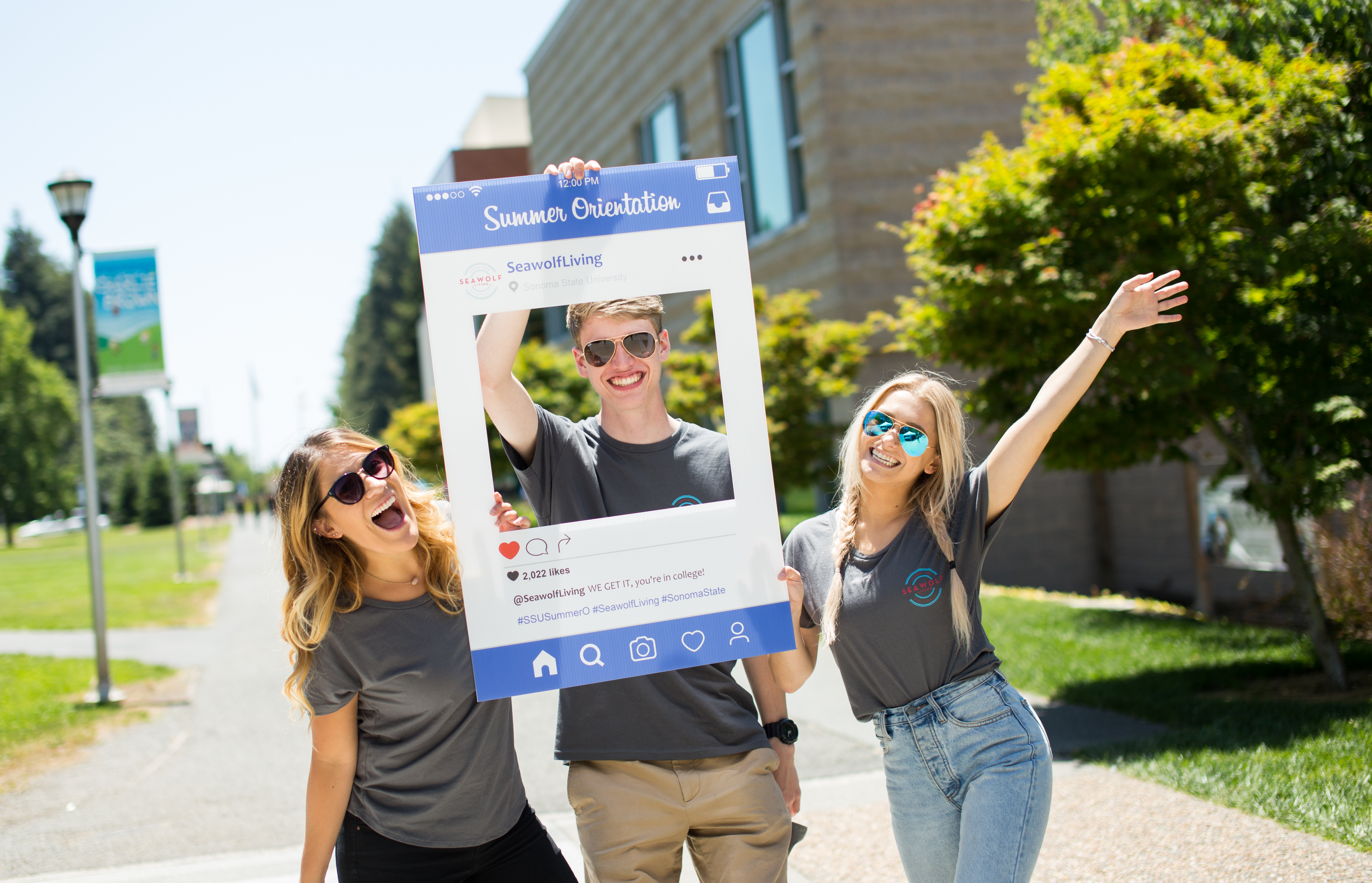 Three students pose with a cardboard cutout